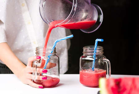 Female pouring watermelon smoothie in a glass jarの写真素材