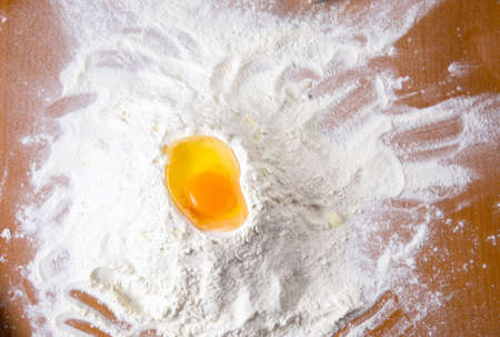 Broken chicken egg on a flour pileの写真素材