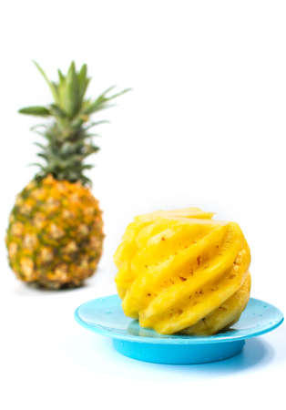 Peeled and sliced pineapple on a blue plateの写真素材
