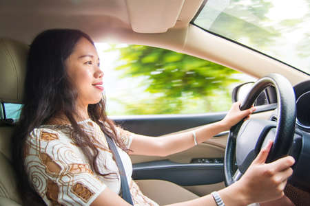 Asian girl driving a car on the highwayの写真素材