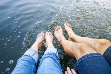 Couple refreshing with their feet in the river waterの写真素材