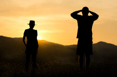 Silhouette of a couple watching romantic sunset on the hillの写真素材