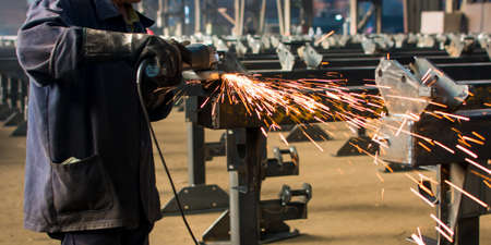 Worker grinding metal with a angle grinder