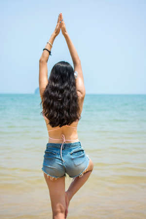 Girl in tree yoga pose on the beachの写真素材