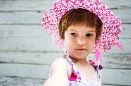 Cute girl wearing hat against vintage wooden backdropの写真素材