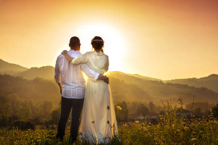 Couple looking at romantic sunset in the field