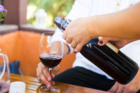 Girl pouring wine to her boyfriend on a dateの写真素材