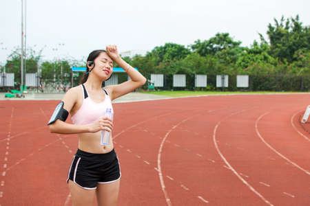 Tired female jogger at the running track on a warm dayの写真素材
