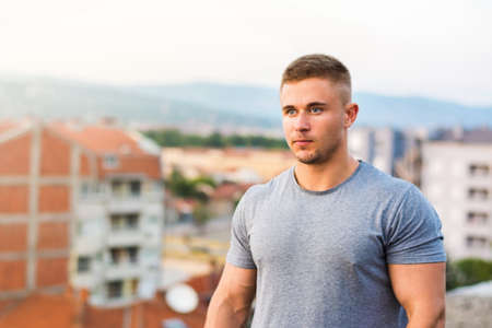 Confident blonde bodybuilder standing on the rooftopの写真素材