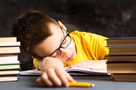 Boy taking a nap while finishing homework by the deskの写真素材