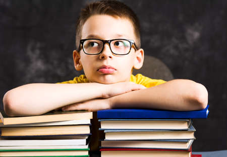 Boy taking a rest on top of piled books