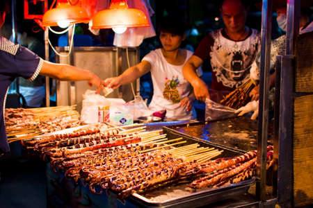 NANNING, CHINA - JUNE 9, 2017: Food on the Zhongshan Snack Street, a food market in Nanning with many people bying food and walking around. This food street is the biggest night food market  in the capital city of Guangxi province in Chinaのeditorial素材