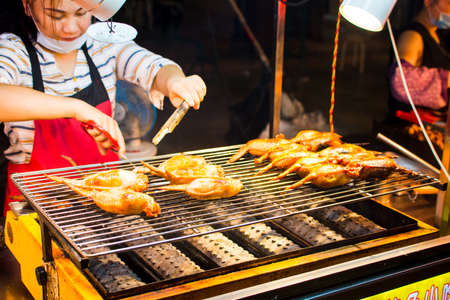 NANNING, CHINA - JUNE 9, 2017: Chinese chef preparing barbecue on the Zhongshan Snack Street, a food market in Nanning. This food street is the biggest night food market  in the capital city of Guangxi province in Chinaのeditorial素材