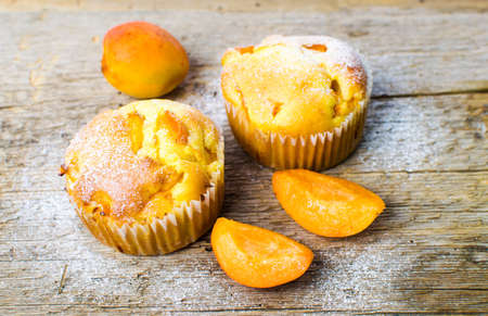 Homemade apricot muffins with fruit on a wooden tableの写真素材