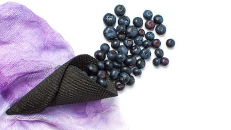 Blueberry fruit falling out of a dark ice cream coneの写真素材