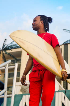 Young African American man holding a surfboard outdoors