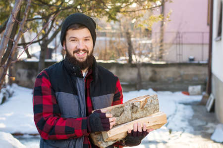 Masculine man carrying firewood for heat in the winterの写真素材