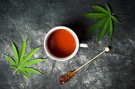 Marijuana tea and leafs on a dark textured backgroundの写真素材