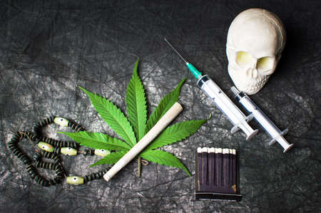 Marijuana leaf and joint with syringes on dark textileの写真素材