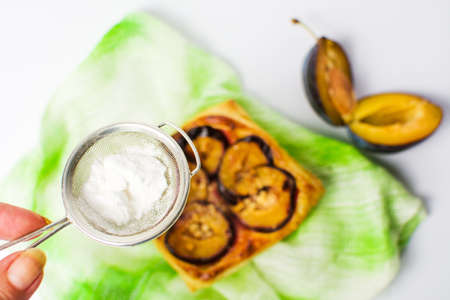 Adding sugar to plum sweet pie sliceの写真素材