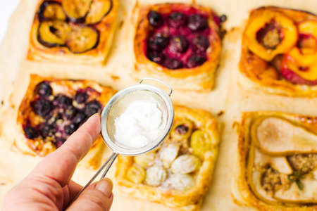 Adding sugar to fruit sweet pie slices on baking paperの写真素材