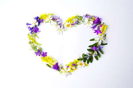 Heart shape made of colorful wildflowers on whiteの写真素材