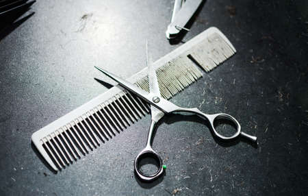 Comb and scissors on a dirty hairdresser tableの写真素材