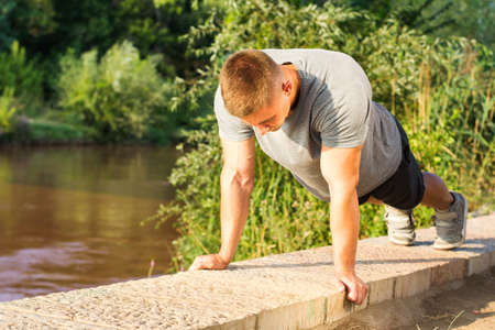 Man performing push ups by the river