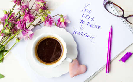 Cup of coffee on and a motivation message with purple flowers