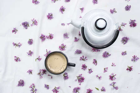 Coffee with milk and purple flowers on white fabricの写真素材