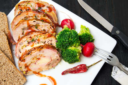 Rolled meat meal with vegetables on white plateの写真素材