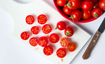 Cherry tomatoes sliced on a white cutting boardの写真素材