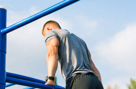 Man performing Russian pull ups on street workout outdoors