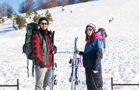 Happy couple with skiing equipment on snowy mountainの写真素材