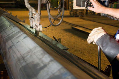 Male worker operating automated steel welding machine