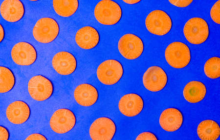 Carrot slices on blue background flat lay patternの写真素材