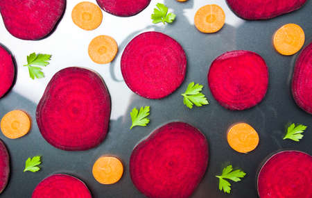 Raw beet and carrot slices isolated on dark background の写真素材