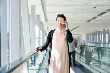 Girl using phone while on the moving walkway insideの写真素材