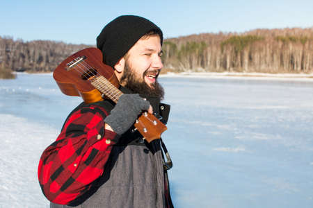 Man with ukelele standing on a frozen lake の写真素材