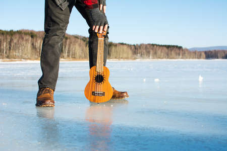 Man with ukelele standing on a frozen lake の写真素材