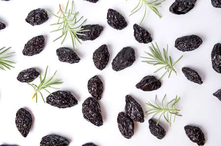Dried plums and rosemary leafs on white backgroundの写真素材