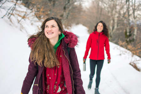 Two girls on a hiking trip on snowy mountain pathの写真素材