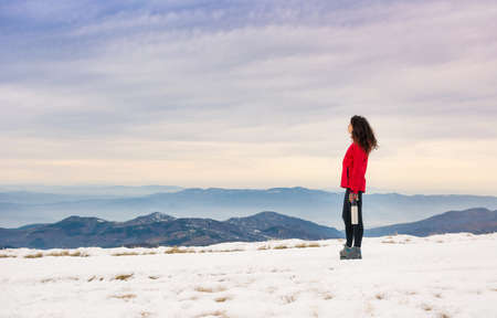 Female hiker admiring winter scenery on a mountaintop aloneの写真素材