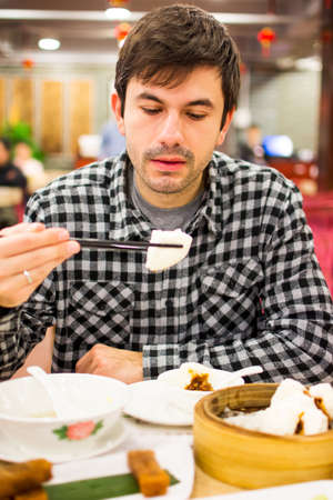 Foreigner enjoying Chinese food in restaurantの写真素材