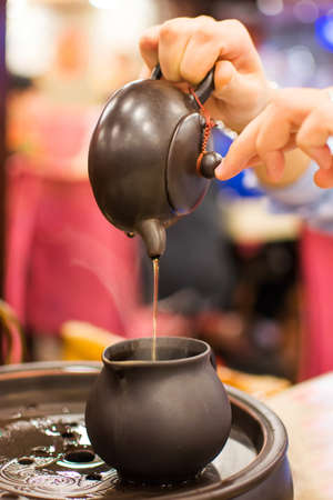 Female's hand pouring tea to tea pot in restaurantの写真素材