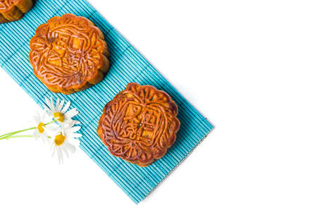 Traditional homemade moon cake on bamboo mat and daisy on white backgroundの写真素材