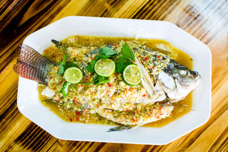 Steamed thai flavor sour and spicy fish served on the plate in restaurantの写真素材
