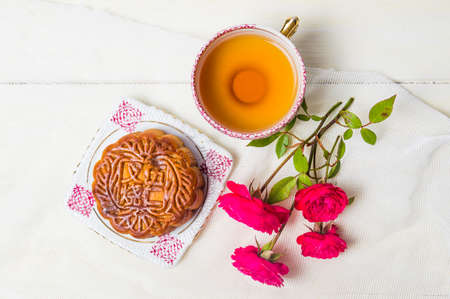 Traditional homemade moon cake with tea and rose served on the tableの写真素材