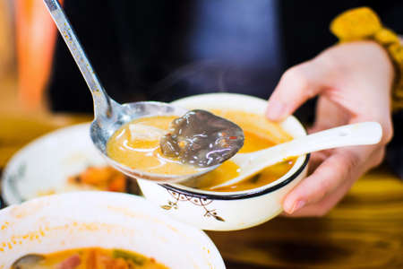 Woman fills a bowl with fresh Tom Yum Gong soup の写真素材