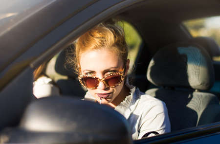 Female driver applying lipstick using rear mirror in a car